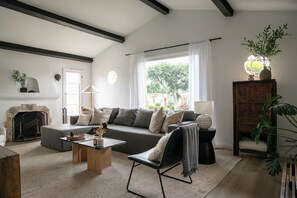 A living room with a fireplace, a sofa, a coffee table, and a lamp. - Casa Mika - Designer Curated 2BR/1BA Retreat Near SoFi, Intuit Dome & The Forum (Los Angeles)