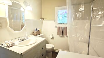 Een badkamer met een dubbele wastafel, toilet, douchegordijn en een raam met bloemendecoratie.