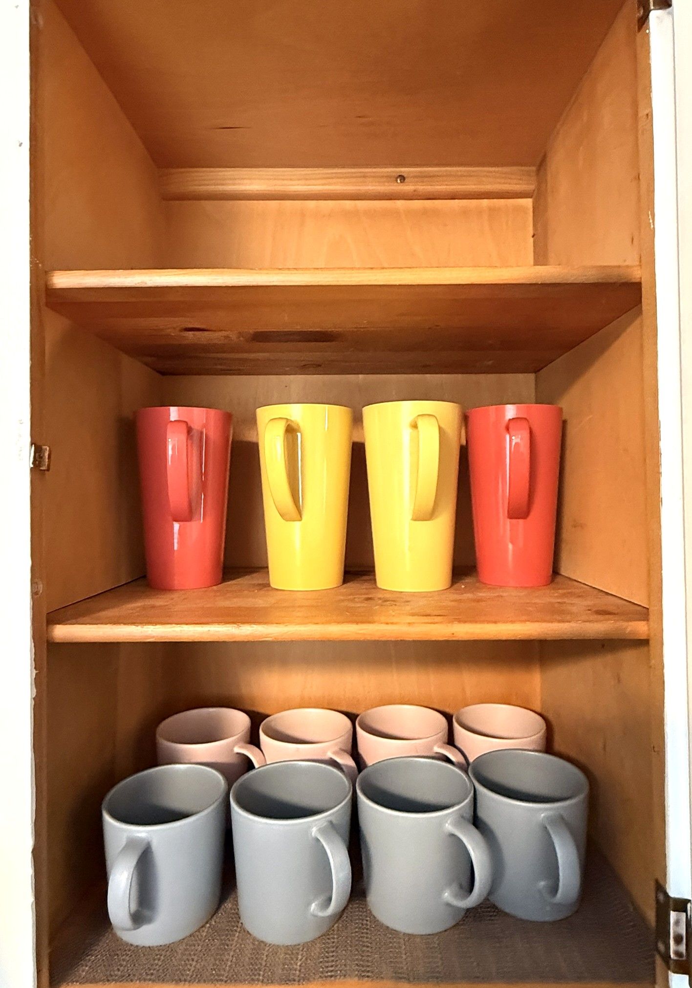 Un meuble en bois doté d’étagères où sont rangées des tasses.