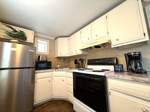 A kitchen with white cabinets, a stainless steel refrigerator, a microwave, a stove, and a coffee maker. - Cute 1-Bedroom in Heart of Berwyn (Berwyn)