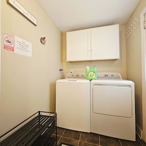 A laundry room with a washer and dryer, a bench, and signs on the wall. - Cute 1-Bedroom in Heart of Berwyn (Berwyn)