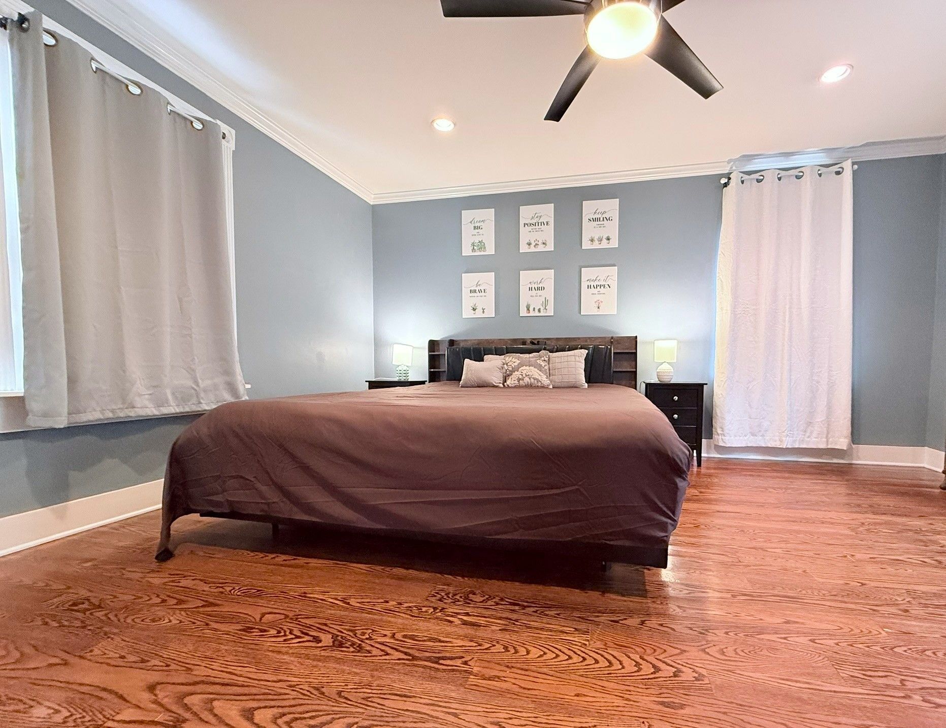 A bedroom with a bed, a ceiling fan, and wall art.