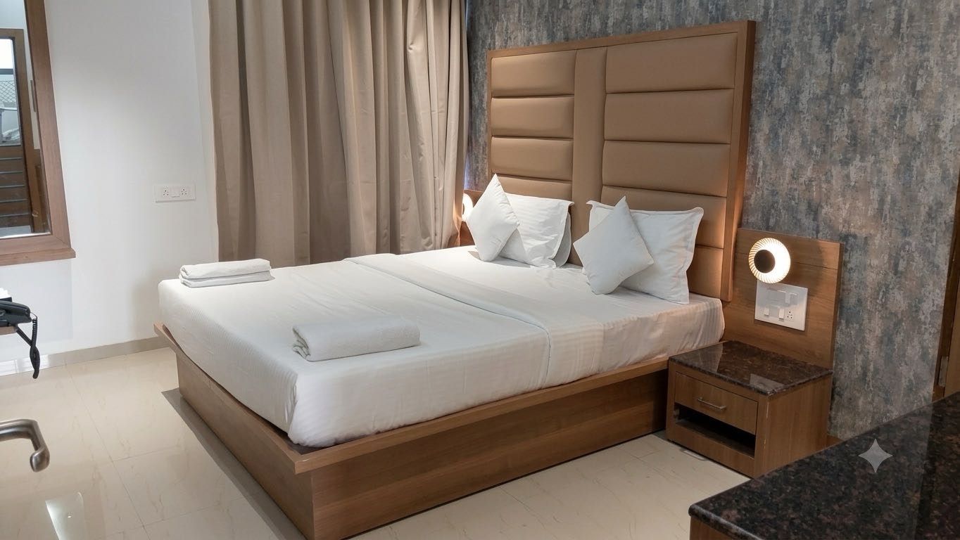 Una cama bien hecha con cabecera de madera, una mesita de noche con lámpara y un baño con espejo y toallero.