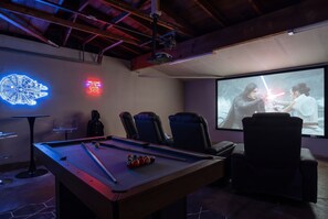 A room with a pool table, two gaming chairs, a projector screen displaying a movie scene, and Star Wars-themed decorations. - Enchanted Stay: Disney, Spa, Theater, Arcade, Playgound (Midway City)