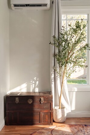 A room corner with a wooden chest, a potted plant, and a window with curtains. - Enchanted Stay: Disney, Spa, Theater, Arcade, Playgound (Midway City)