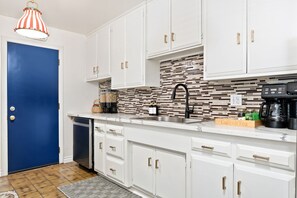 A modern kitchen with white cabinets, a black faucet, and a tiled backsplash. - Enchanted Stay: Disney, Spa, Theater, Arcade, Playgound (Midway City)
