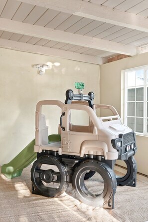 Um caminhão de brinquedo em um quarto com janela, teto branco e parede verde.