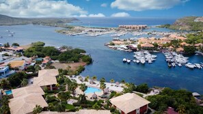 A marina with numerous boats docked, surrounded by residential buildings and lush greenery. - La Marina | 2BR Waterfront + Marina Views (Brakkeput)
