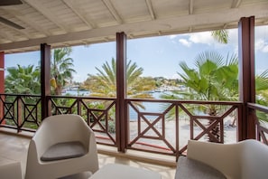 A covered outdoor seating area with a view of a marina and beach. - La Marina | 2BR Waterfront + Marina Views (Brakkeput)