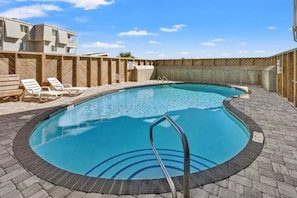 A swimming pool with a wooden deck, lounge chairs, and a clear blue sky. - Sea Oats | 3BR Oceanfront Escape (North Myrtle Beach)