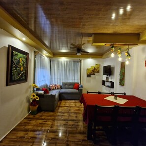 A living room with a sofa, a dining table, and a ceiling fan. - Green Paradise Home. (Provincia de Alajuela)