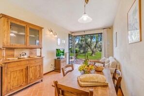 A dining area with a wooden table, chairs, and a view of the outdoors through large windows. - Chianti Site Apt Fontana Shared Pool|4, Castelfiorentino, Italy (Castelfiorentino)