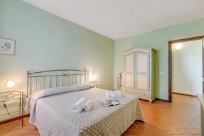 A neatly made bed with a quilt, two bedside lamps, a framed picture on the wall, and a wardrobe with a mirror. - Chianti Site Apt Prato Shared Pool| 4, Castelfiorentino, Italy (Castelfiorentino)
