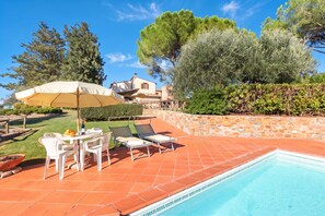 A pool area with a tiled deck, lounge chairs, and a table with chairs. - Chianti Site Apt Prato Shared Pool| 4, Castelfiorentino, Italy (Castelfiorentino)