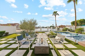 Zona de piscina amb gandules, una llar de foc i una piscina.