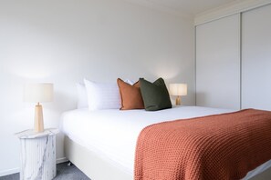 A hotel room with a bed, two bedside lamps, a marble side table, and a large window. - The Mersey Luxe Retreat (East Devonport)