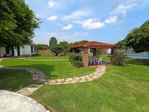 A backyard with a patio, a swimming pool, and a stone pathway. - Country Cottage in Morelos · Private Pool · Pet-Friendly (Fraccionamiento Paraíso Tlahuica)