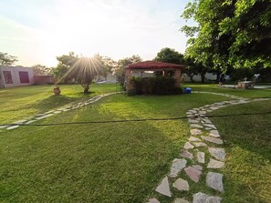 A well-maintained lawn with a stone pathway leading to a brick structure. - Country Cottage in Morelos · Private Pool · Pet-Friendly (Fraccionamiento Paraíso Tlahuica)