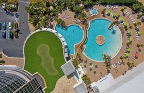 Ein Resort mit einem großen runden Pool, einem kleineren rechteckigen Pool und einer Grünfläche.