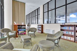 Eine Bibliothek mit Korbstühlen, Bücherregalen und großen Fenstern.