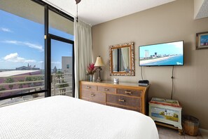 Habitació d'hotel amb un llit gran, una petarrera, un televisor fixat a la paret i vista a la ciutat per la finestra.