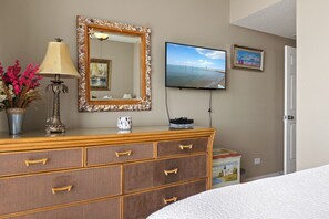 Ein Hotelzimmer mit einem Holzkasten, einer Lampe, einem Fernseher und einem gerahmten Bild an der Wand.