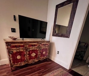 A room with a wooden entertainment center, a flat-screen TV, a mirror, and a patterned rug. - Live Like a Local in this Spacious Ground Level Condo -close to Dining & Skiing❄️ (Edwards)