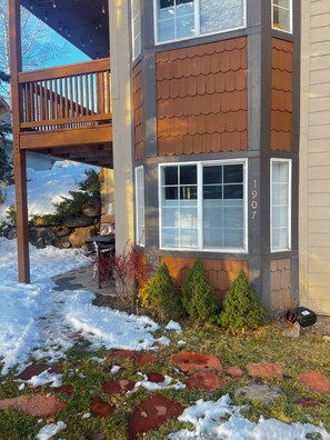 Un immeuble à plusieurs étages doté d’une terrasse en bois, d’un mur en pierre et d’un sol recouvert de neige.