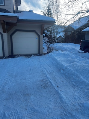 A residential driveway with a garage, snow-covered ground, and a clear sky. - Live Like a Local in this Spacious Ground Level Condo -close to Dining & Skiing❄️ (Edwards)