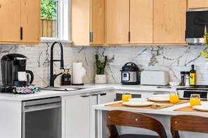 Een moderne keuken met een koffiezetapparaat, een broodrooster en een eethoek met een tafel gedekt voor twee personen.