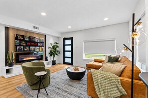 A modern living room with a television, a bookshelf, a sofa, a coffee table, and a potted plant. - Stylish Japandi 1BR-Bishop Arts-Nr Downtown Dallas (Dallas)