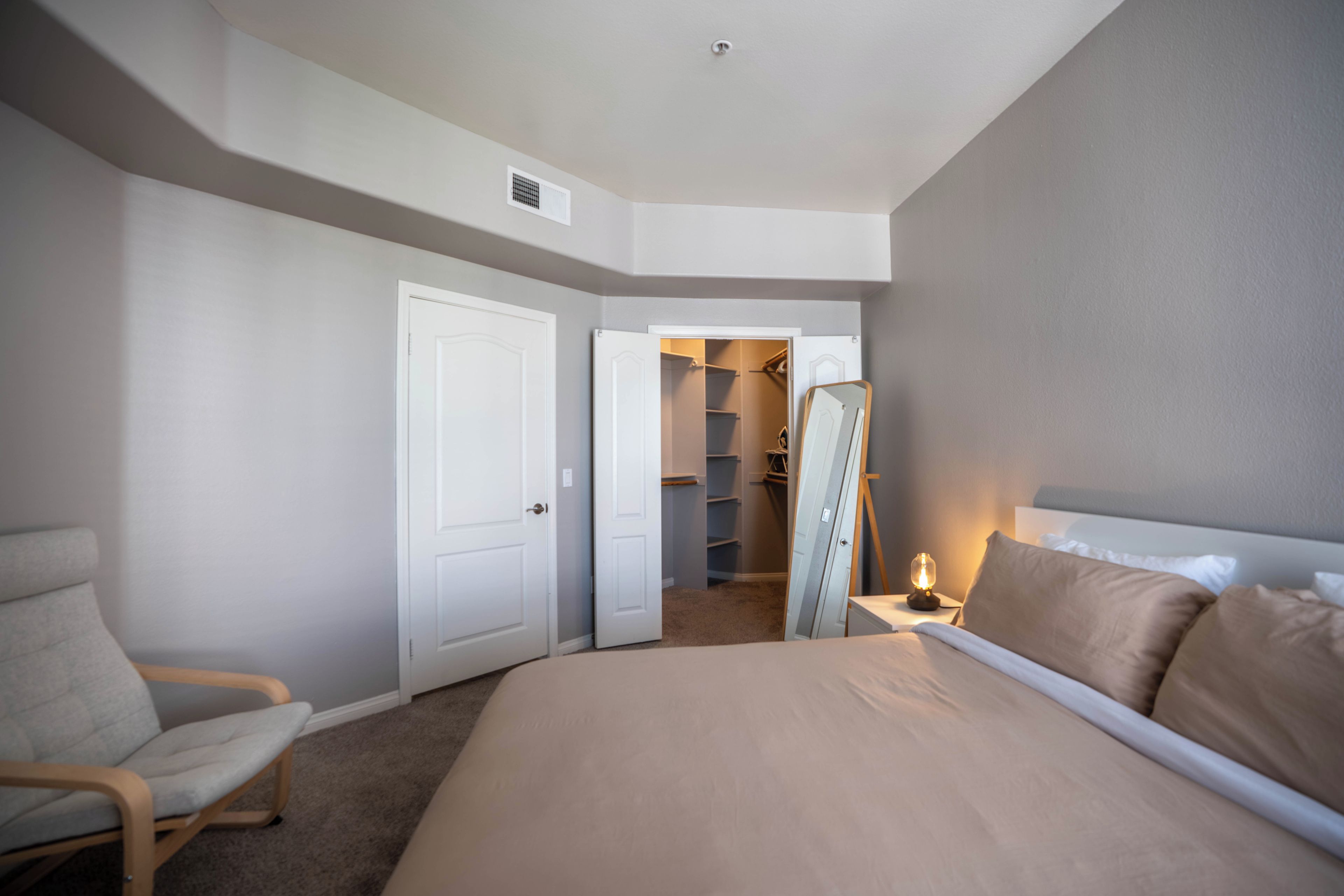 Ein Schlafzimmer mit Bett, Stuhl, Kleiderschrank und Spiegel.