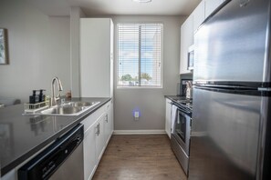 A modern kitchen with stainless steel appliances, a dishwasher, and a window with blinds. - Cozy 1-bedroom apartment in Marina del Rey (Marina del Rey)