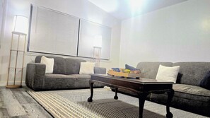 A living room with a grey sofa, a coffee table, and a floor lamp. - Modern Tulsa Retreat  Stylish 3BR Home Near Downtown & Local Attractions (Tulsa)