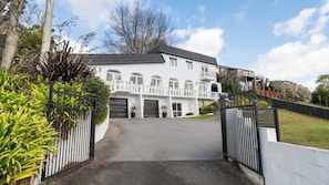 A two-story house with a gated driveway and a balcony. - The White Terraces - Spa Pool, Sleeps 10 (Rotorua)