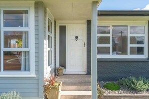 Step up to the front door - a welcoming entrance framed by garden beds. - Huia Nest - Walk to Golf & Stadium, Sleeps 8 (Rotorua)