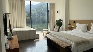 A bedroom with a large bed, a wooden bench, a nightstand, a lamp, and a view of a lake through a window. - ZHU85 (Lishui)