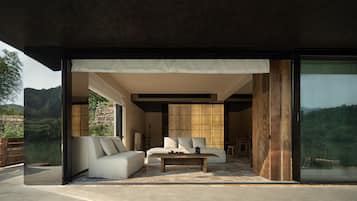 Een modern interieur met een bank, een bijzettafeltje en een grote schuifdeur naar een prachtig buitengebied.