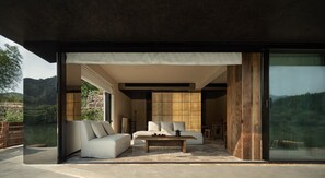 A modern interior with a sofa, a coffee table, and a large sliding glass door leading to a scenic outdoor area. - ZHU85 (Lishui)