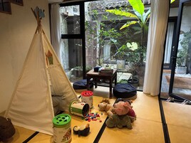 Habitación con zona de juegos que incluye una carpa, juguetes y una mesa con libros.
