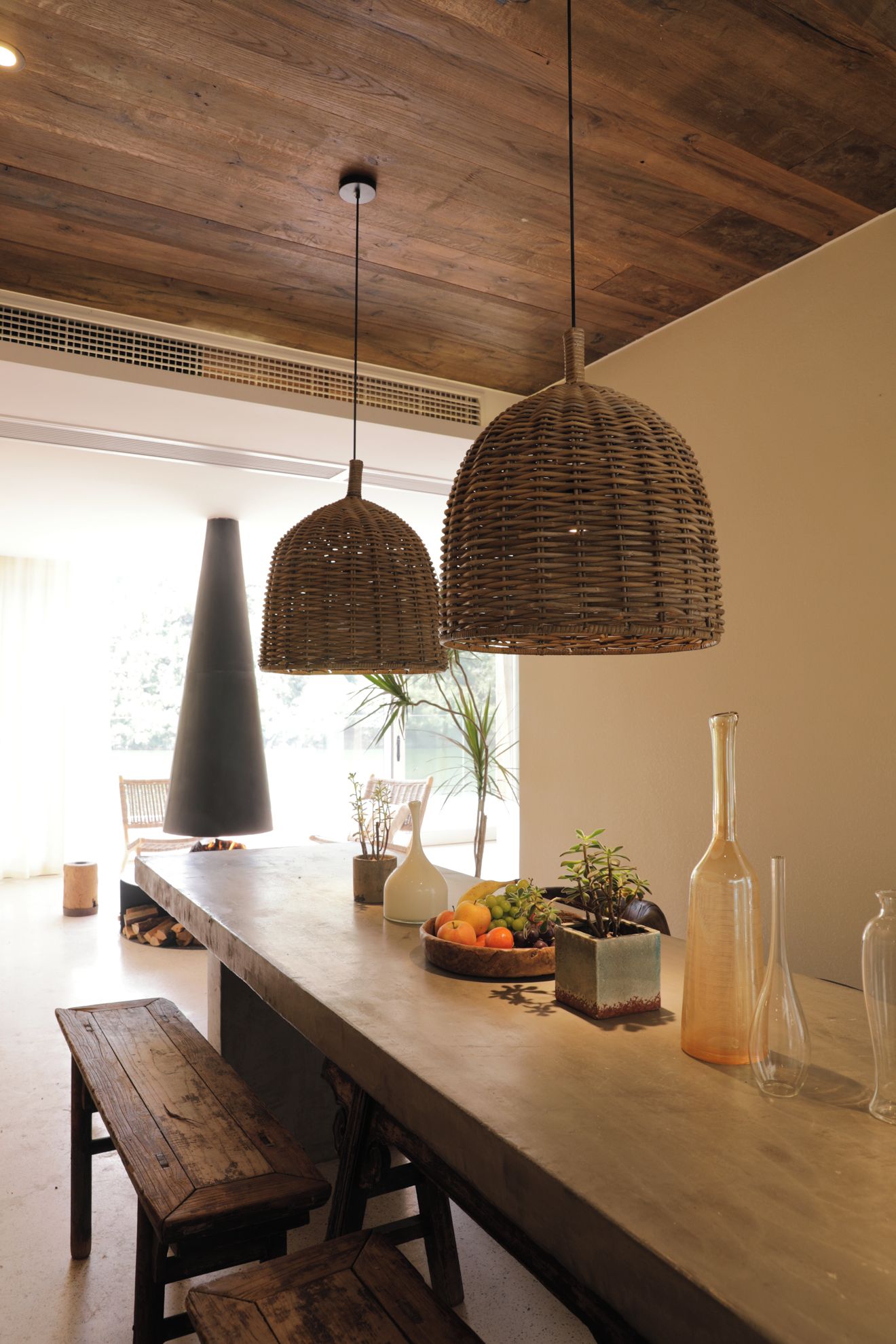 Una cucina con un lungo bancone, lampade a sospensione in vimini e una panca.