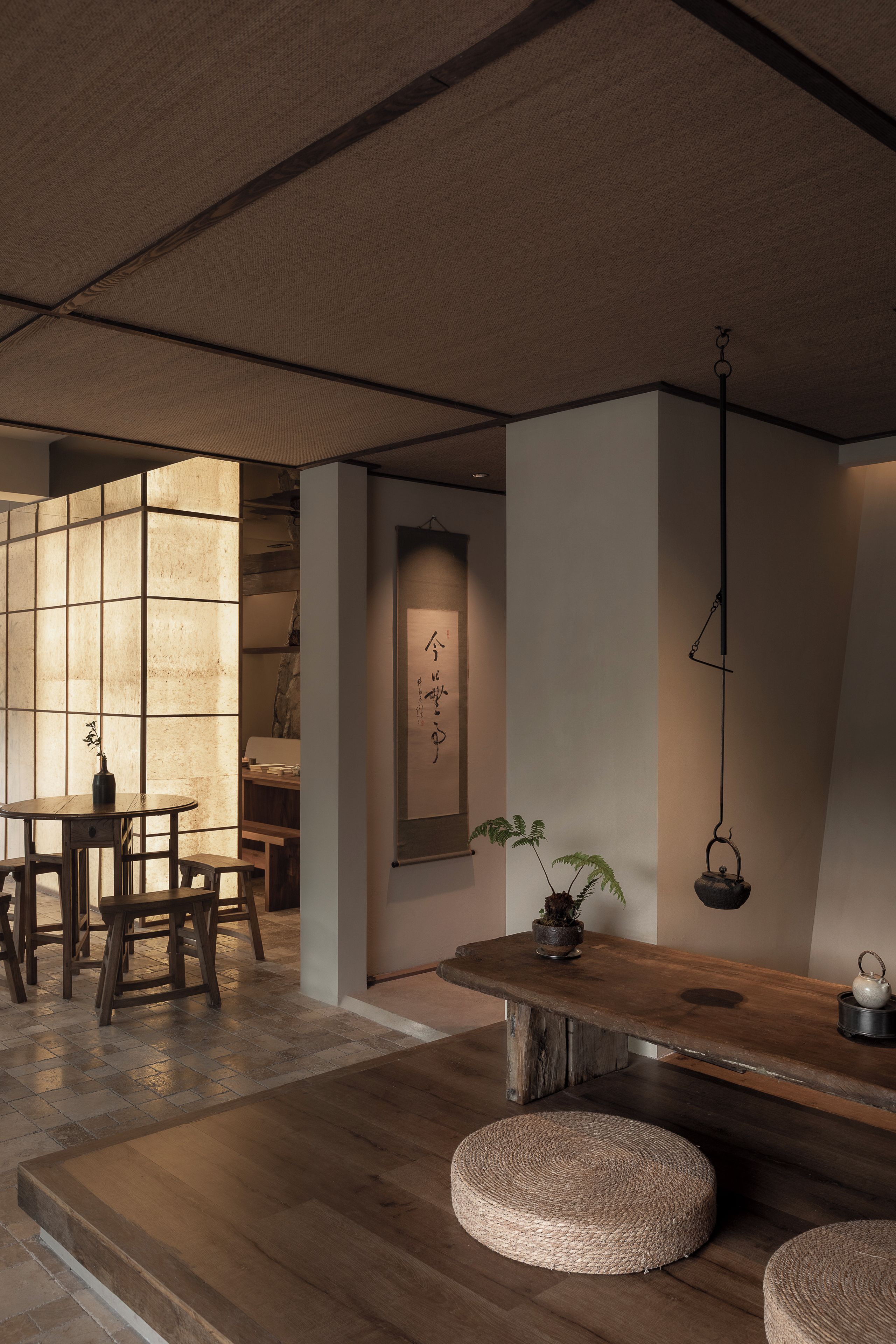 A traditional Japanese interior with tatami flooring, a low wooden table, and a hanging light fixture.
