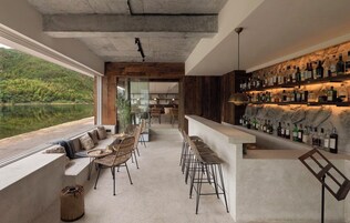 Zona de bar moderna con una barra larga, taburetes y vistas a un lago.