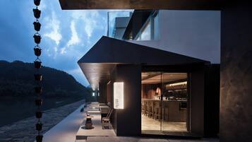 Un edificio moderno con entrada de vidrio, asientos al aire libre y vista al agua.