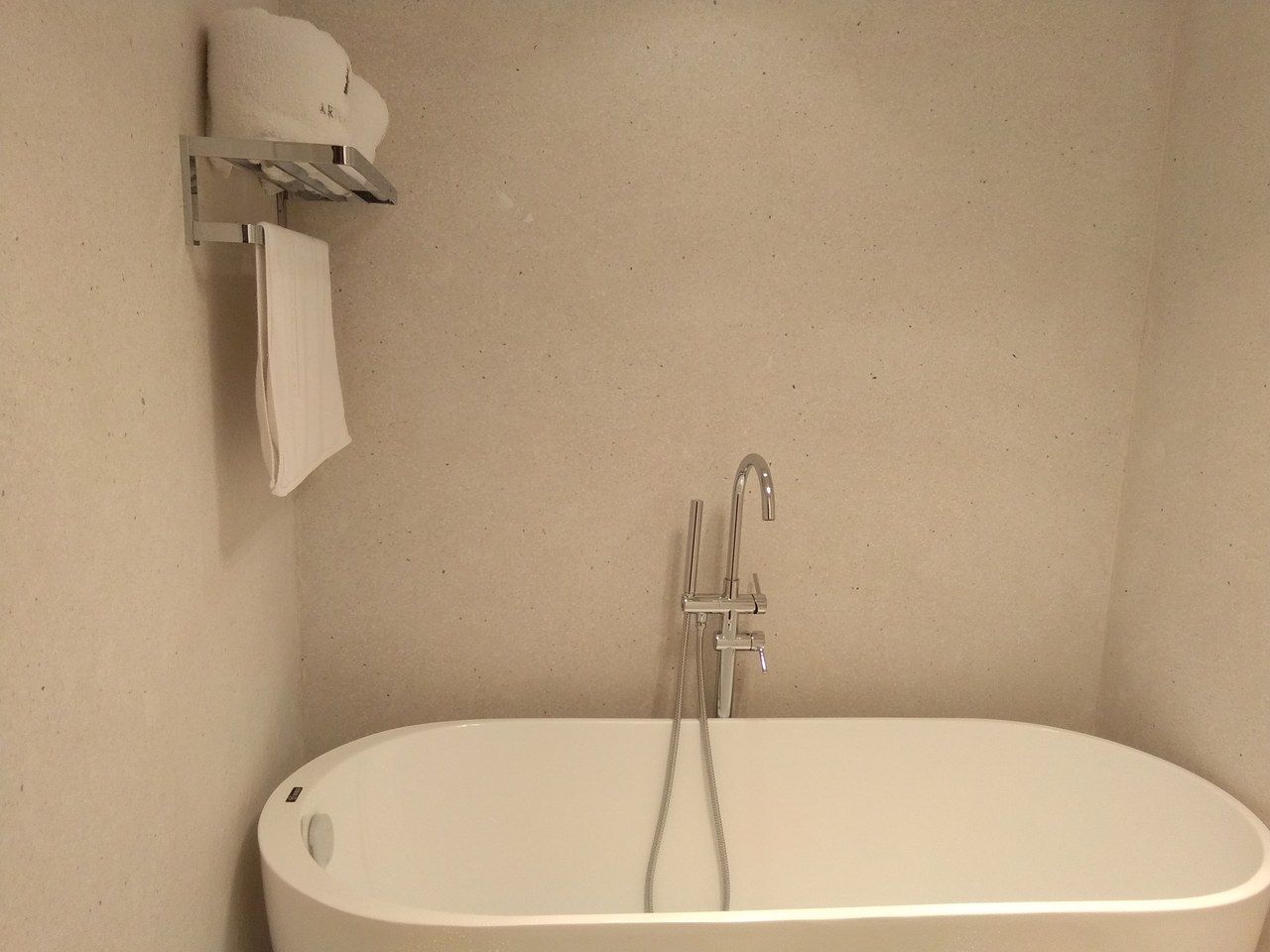A bathroom with a freestanding bathtub, a towel rack, and a showerhead.