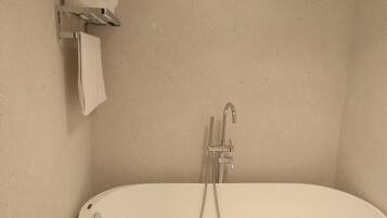 A bathroom with a freestanding bathtub, a towel rack, and a showerhead.