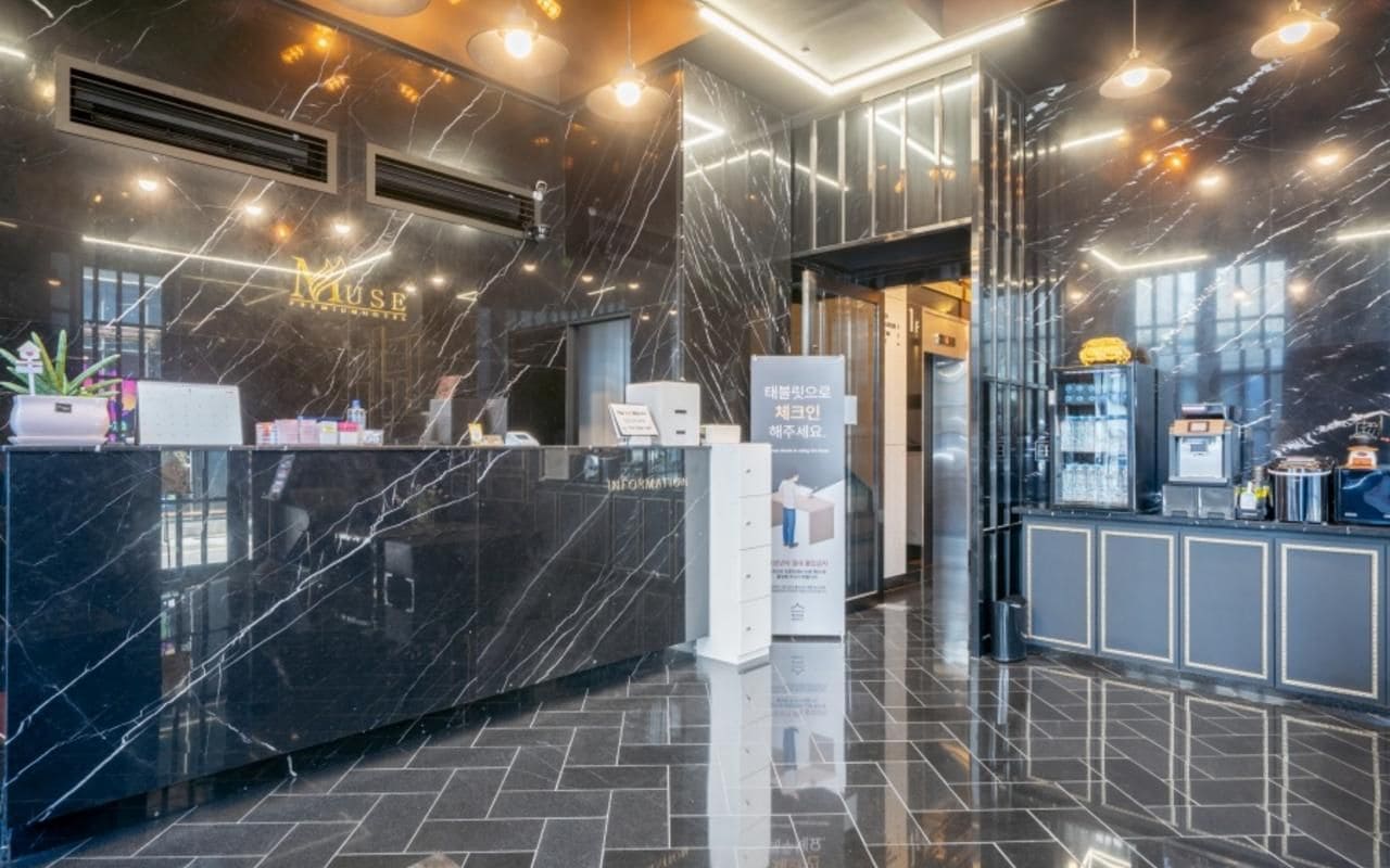 A modern reception area with a marble reception desk, a digital information board, and a well-lit interior.
