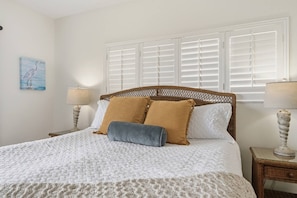A bed with a white quilt, two pillows, and a gray throw. There are two bedside tables with lamps. - Golden Coast | Amazing Ocean Views | 2 pools (St. Augustine Beach)