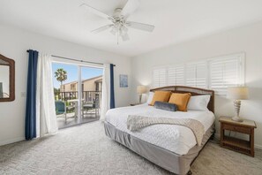 A bedroom with a bed, a ceiling fan, a nightstand, and a view of the outside. - Golden Coast | Amazing Ocean Views | 2 pools (St. Augustine Beach)