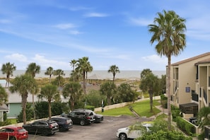 A parking lot with several cars, a building with a beach view, and palm trees. - Golden Coast | Amazing Ocean Views | 2 pools (St. Augustine Beach)